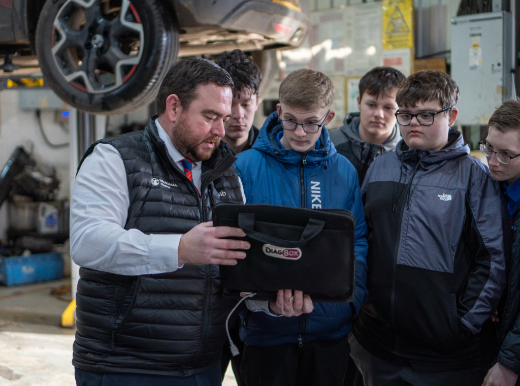 A group of young boys looking at a diag-box their teacher is holding