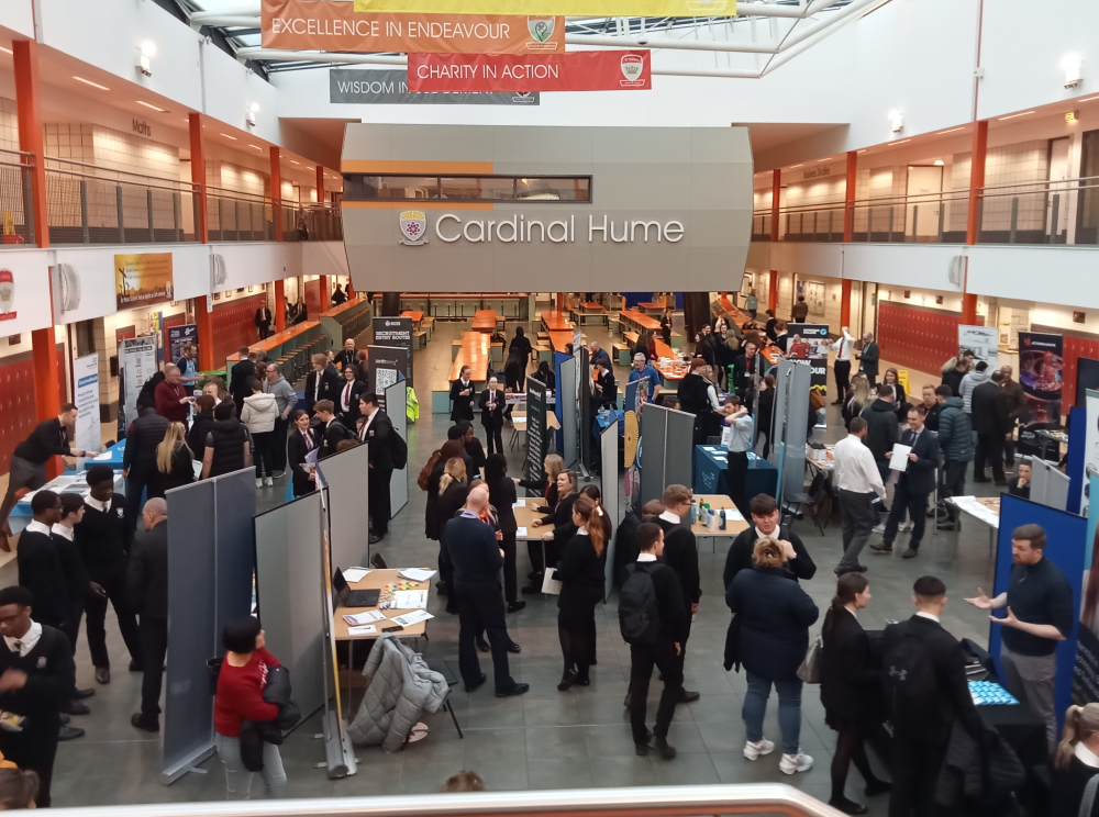 School students moving between stands at a careers fair in their school hall