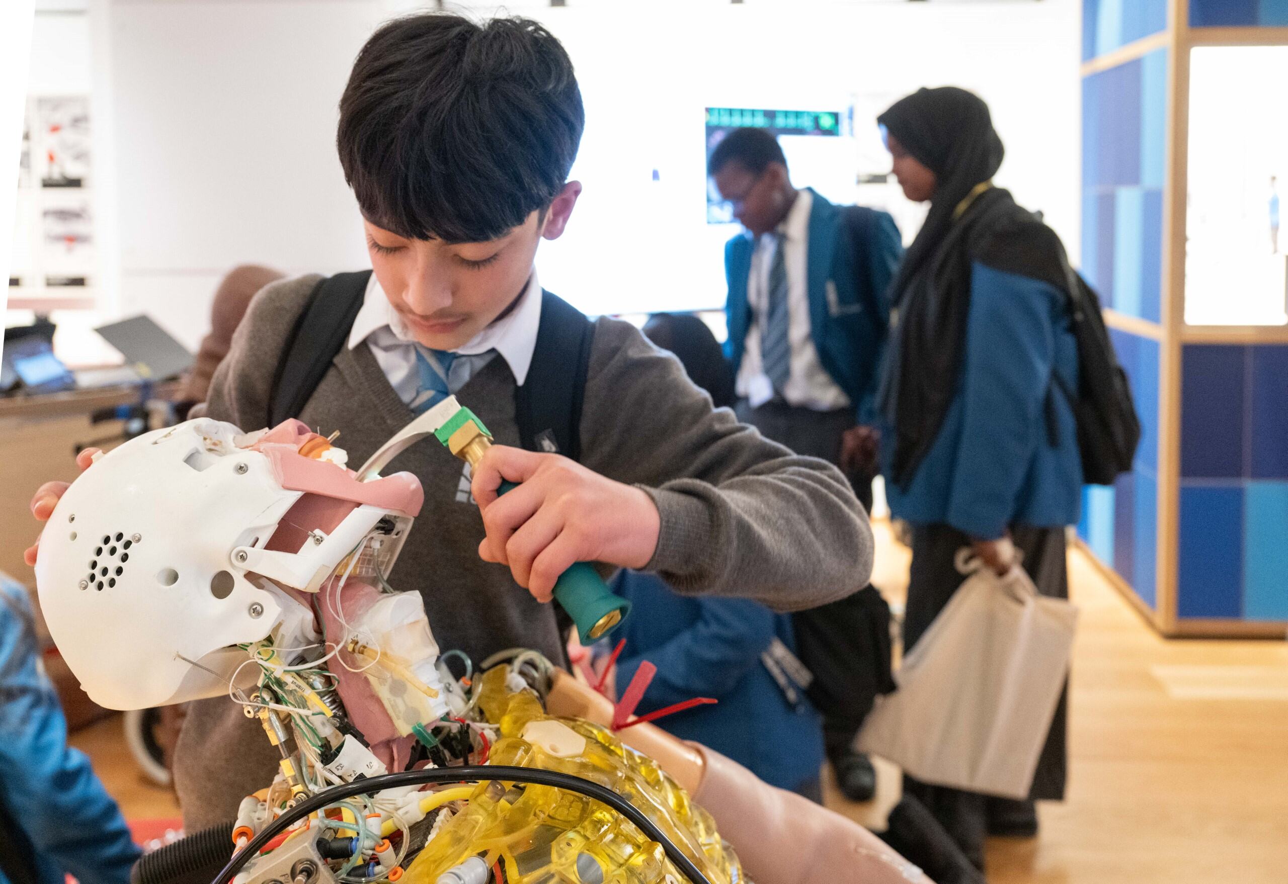 A student bends over a medical dummy as part of an employee demonstration at the Science Museum