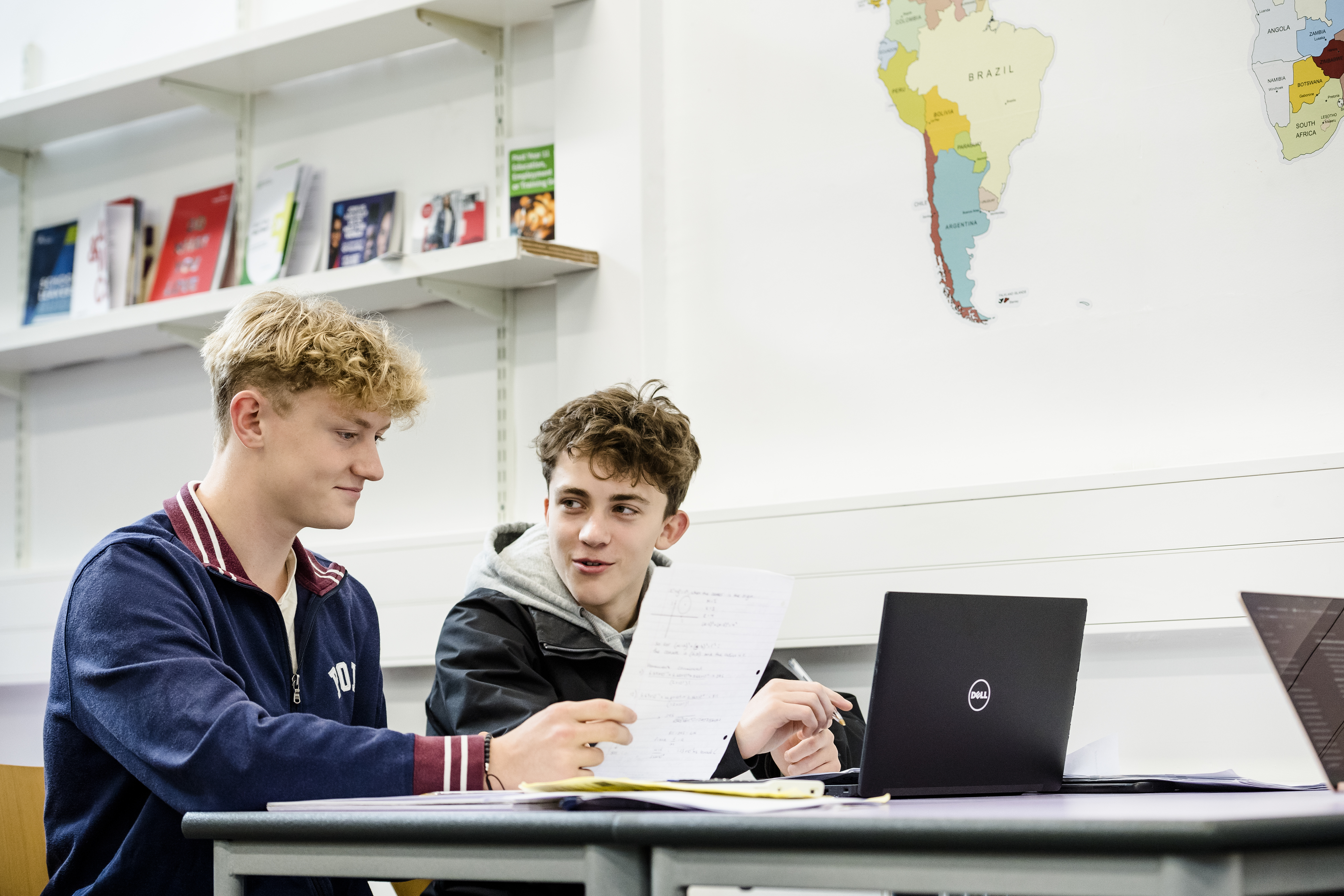 Two school pupils in discussion at a desk