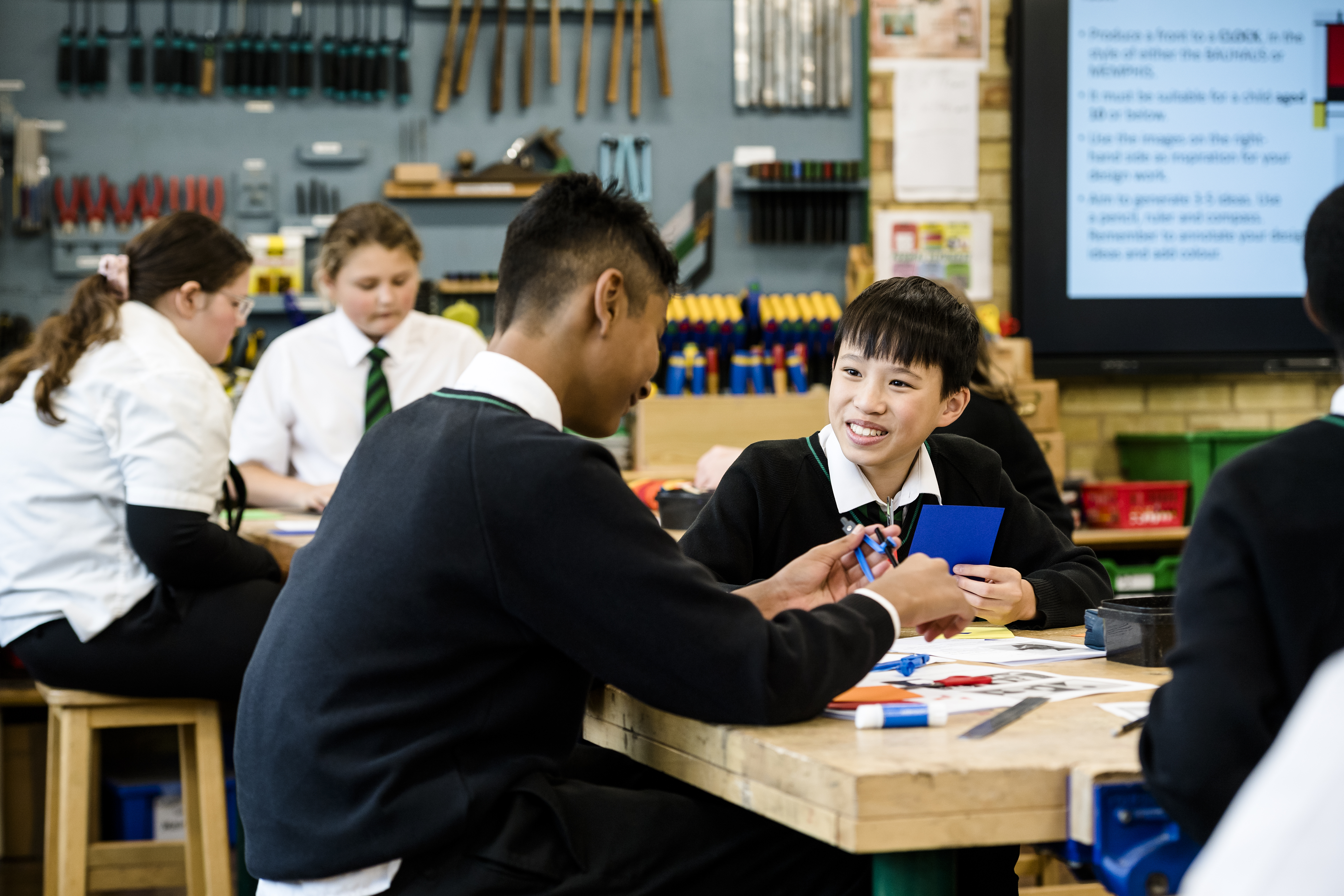 Two students sat at a desk talking and smiling